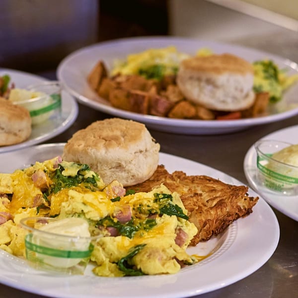 Plates of 5 Spot breakfast with scrambled eggs, hash browns, and biscuits.