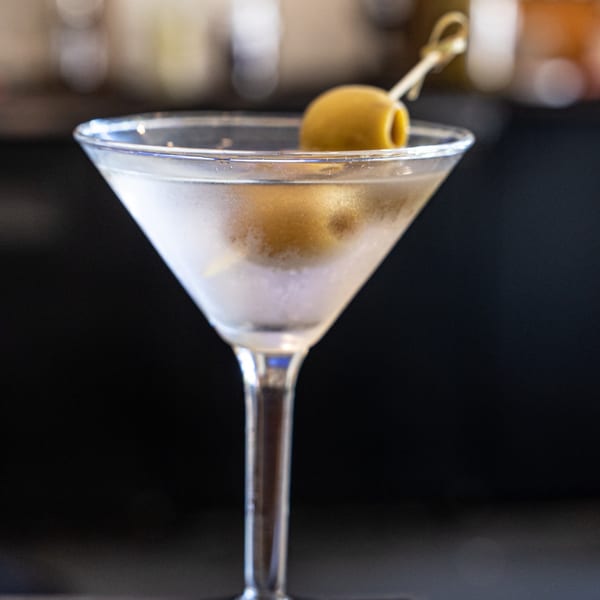A chilled martini in a stemmed glass, garnished with two green olives on a pick.
